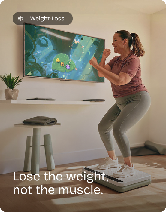 Woman squats with fists raised on the Kiwii Move vibration plate, playing a game on the TV. Weight-Loss: Lose the weight, not the muscle.